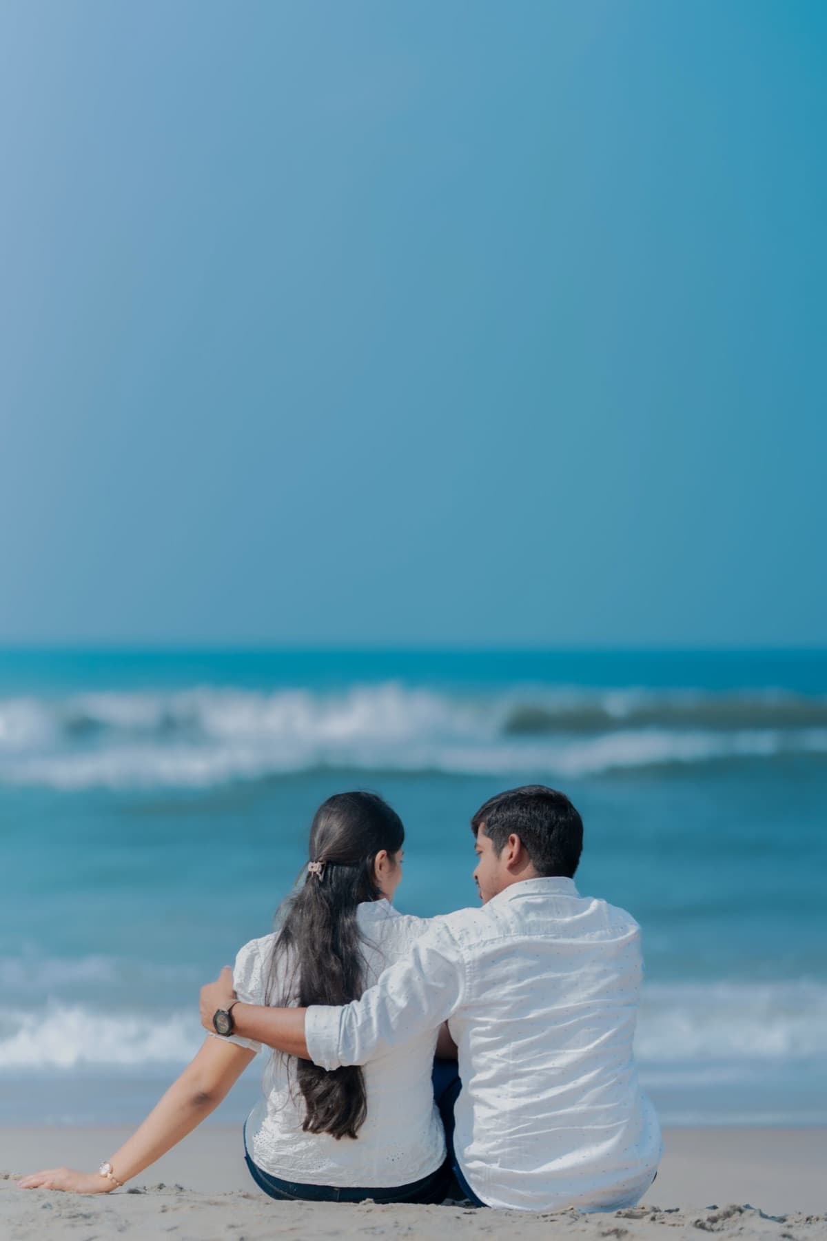 Couple sitting on the beach looking out to sea