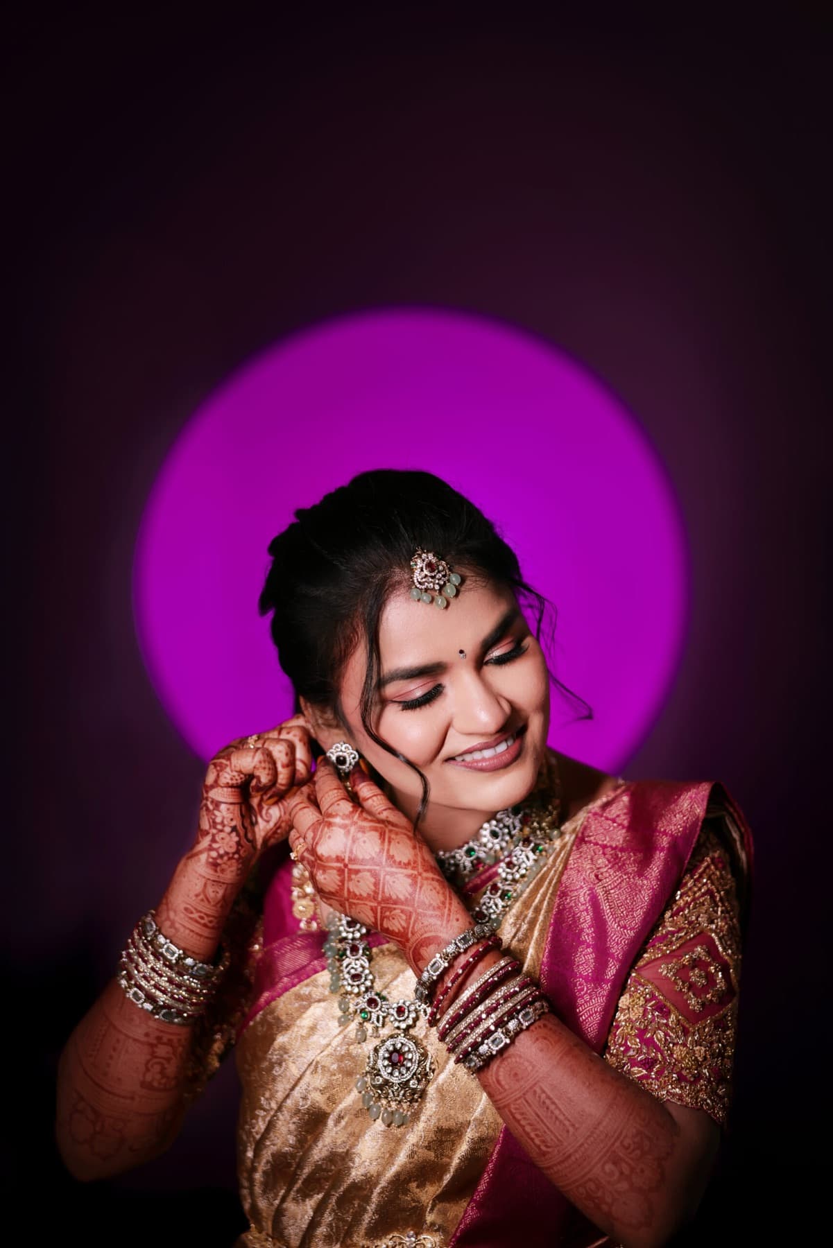 Smiling bride in a silk saree framed by a purple ring light