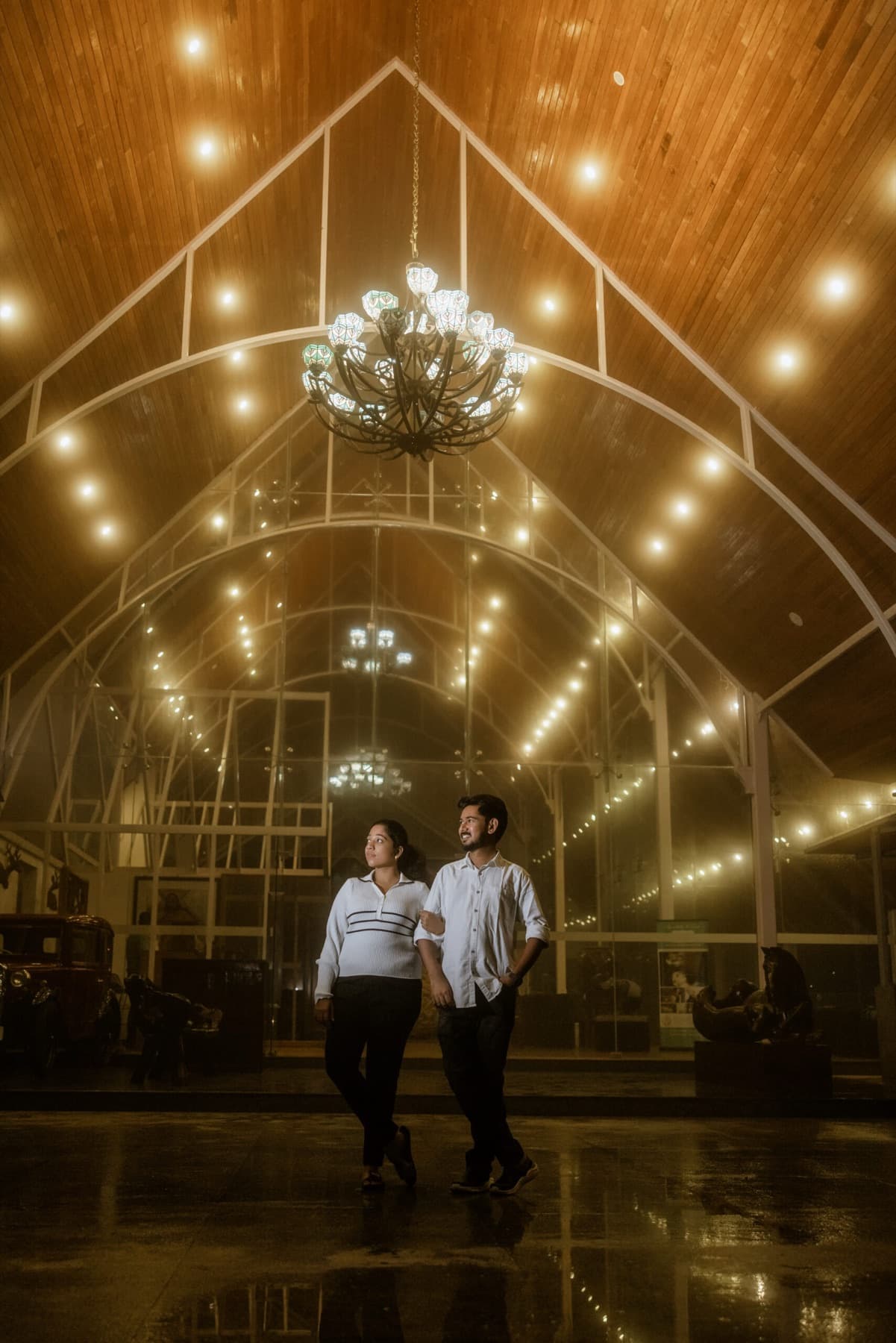 Couple walking through a glasshouse lit with warm lights