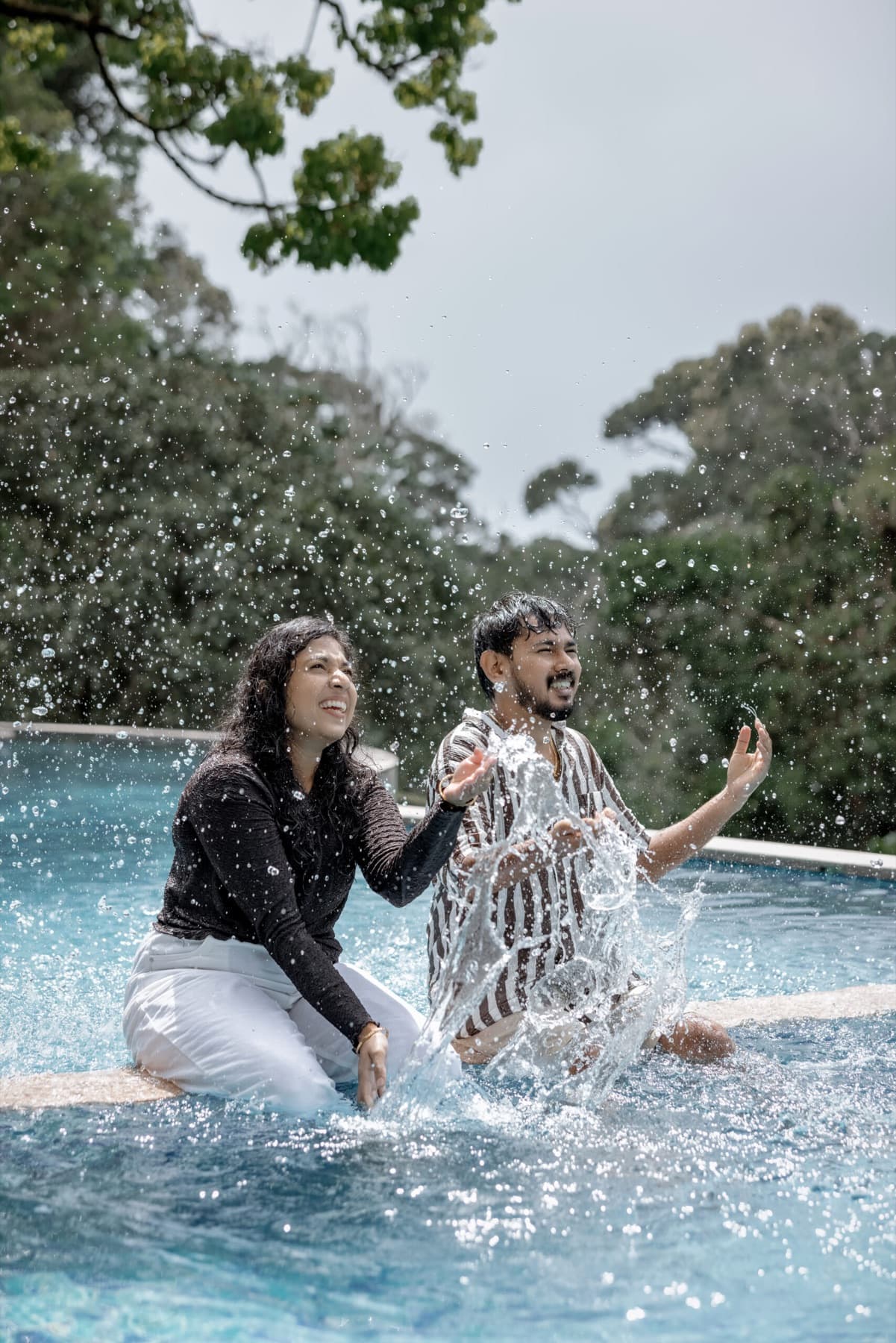Couple splashing water in a pool during a fun shoot