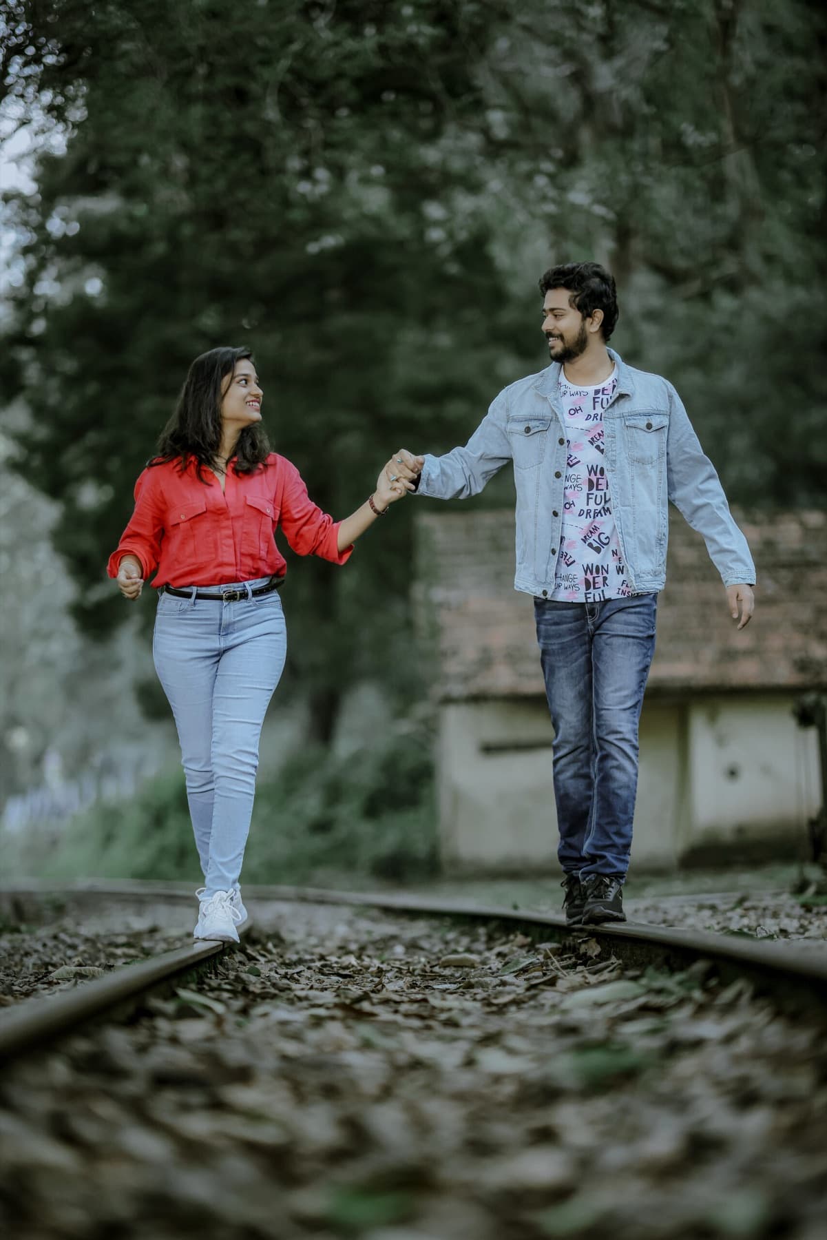 Couple walking hand in hand along a railway track