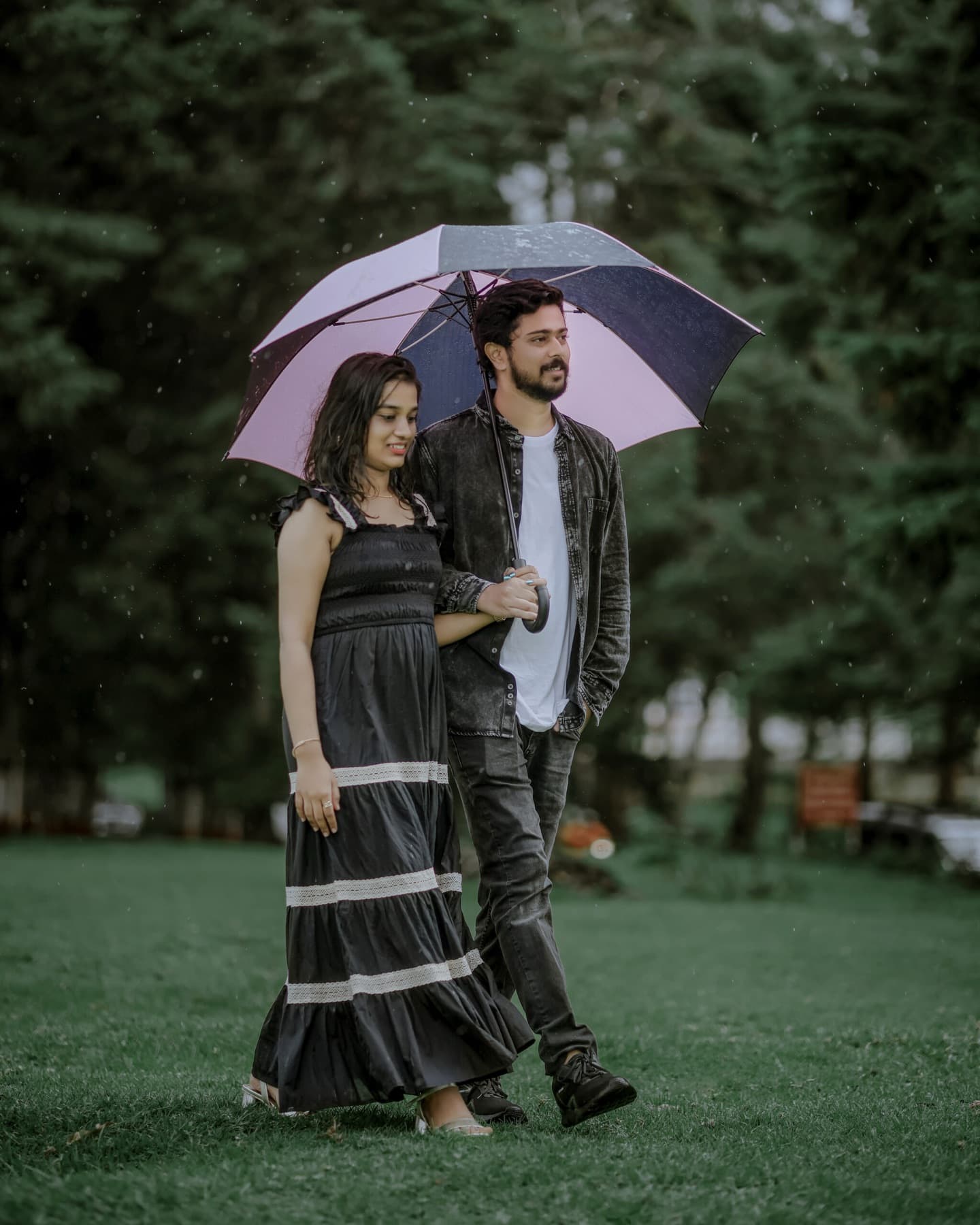 Couple walking together under an umbrella on a lawn