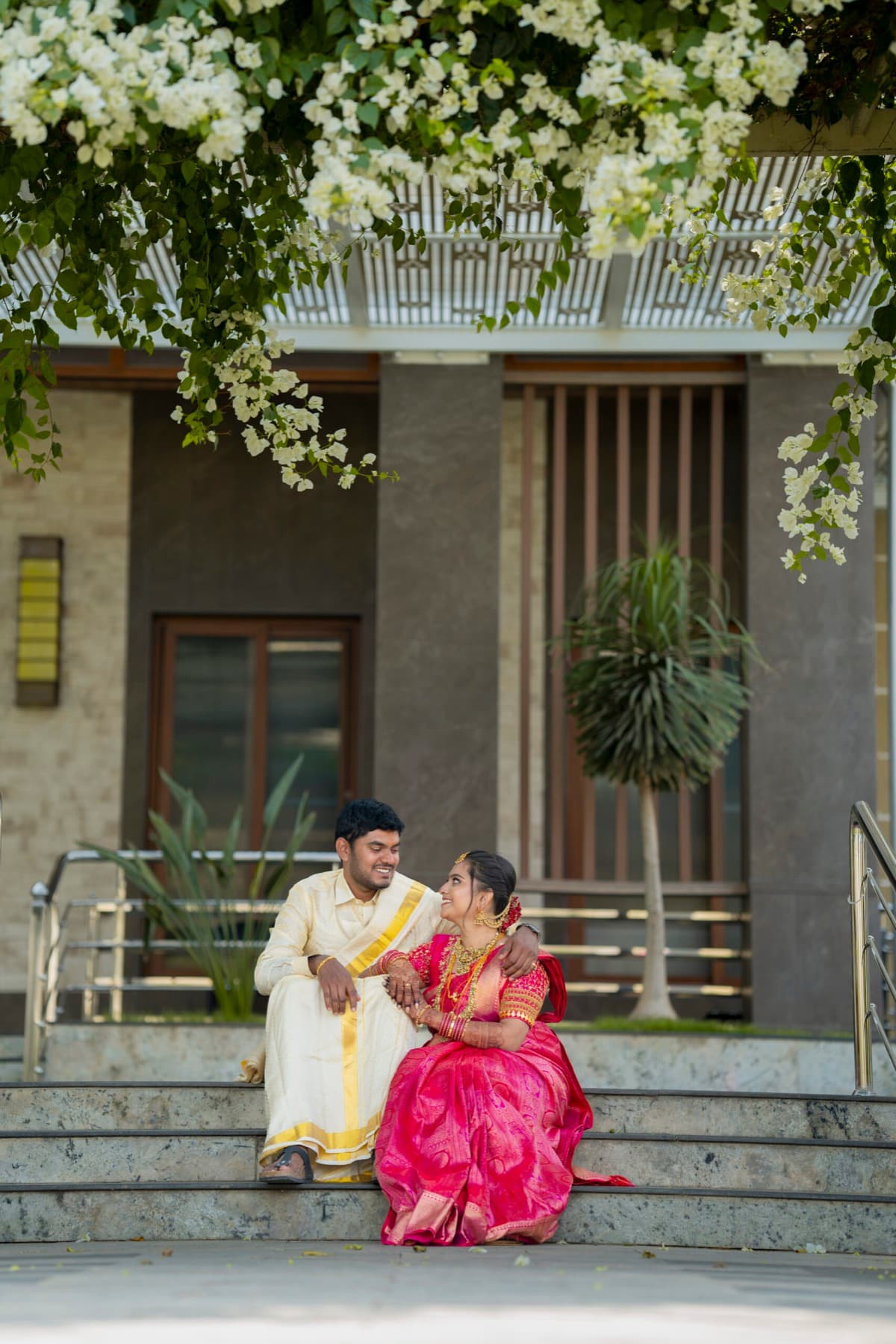Newly married couple in traditional attire seated on steps