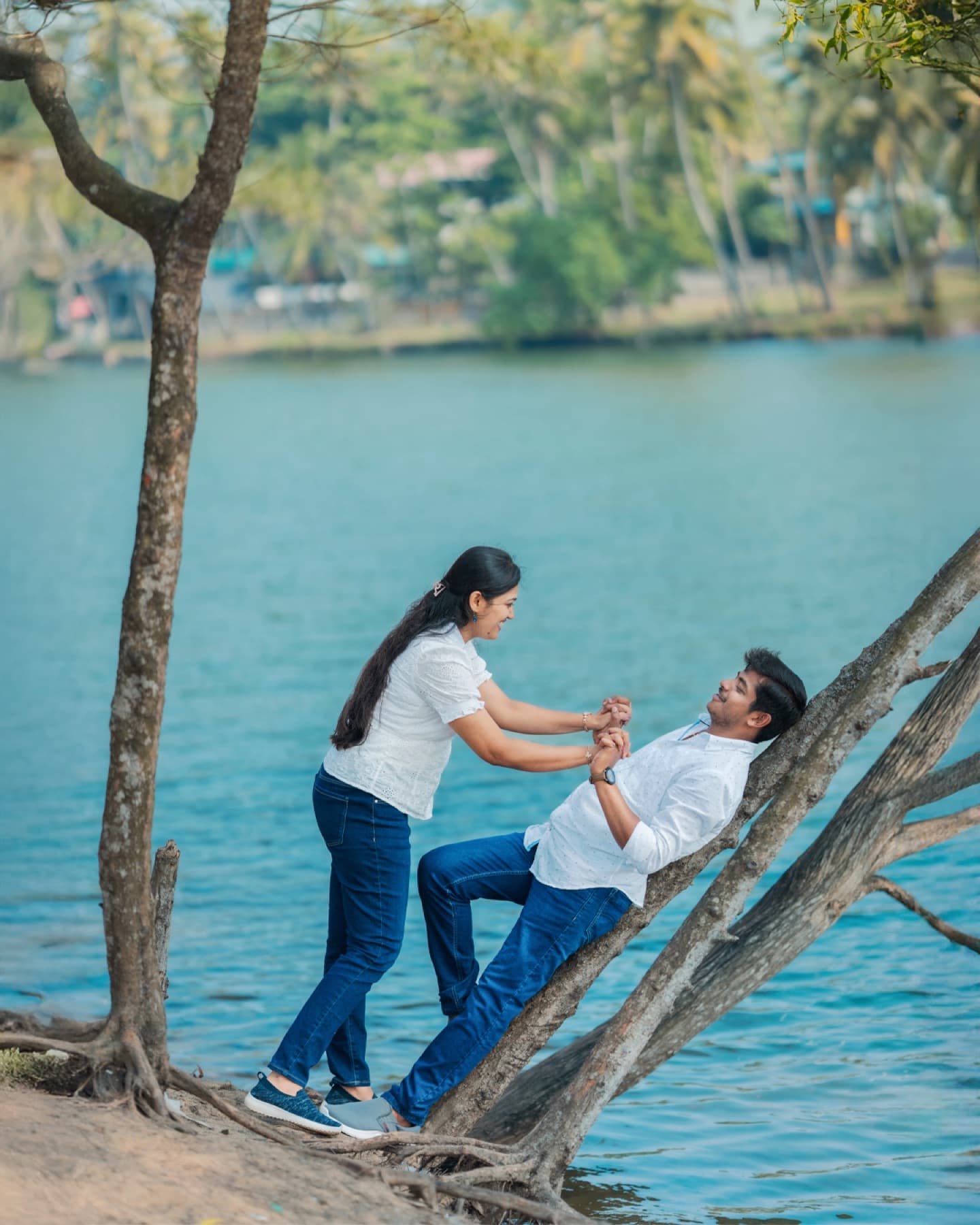 Playful couple on a tree by the lake in a pre-wedding shoot