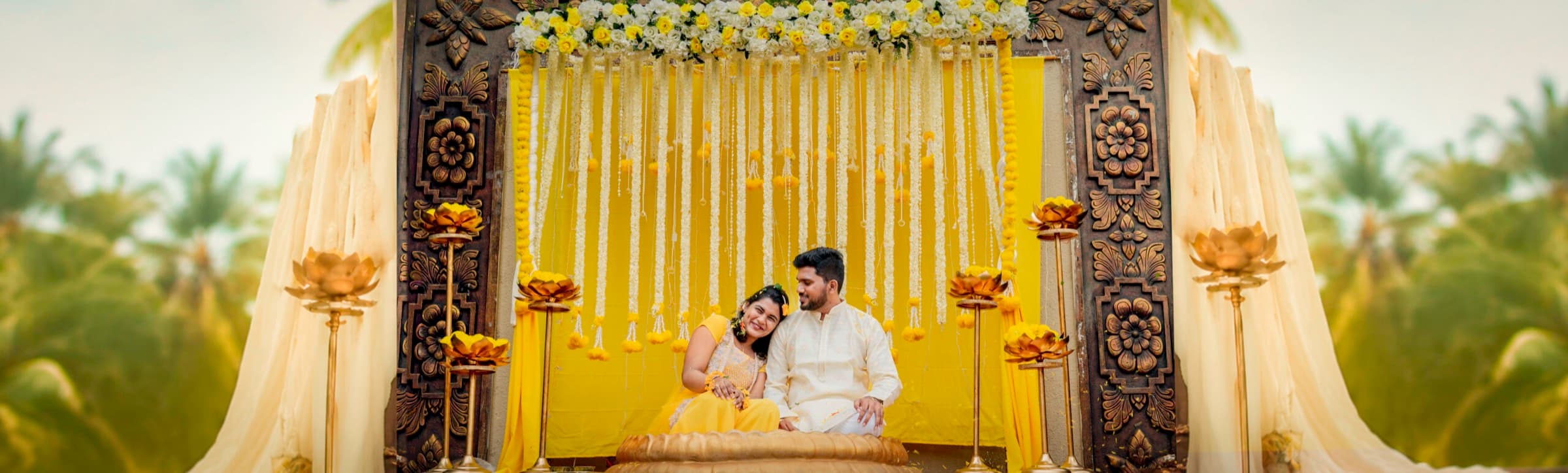 Couple seated on a yellow decorated mandap