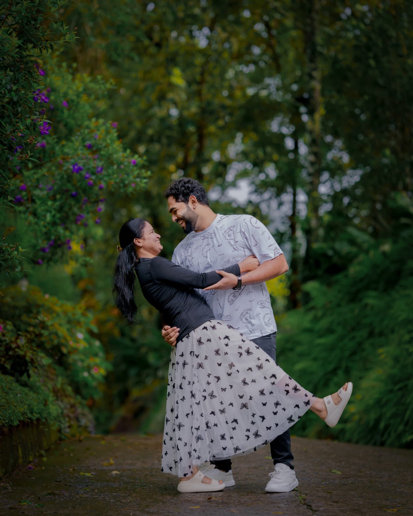 Couple dancing on a forest path during their pre-wedding shoot