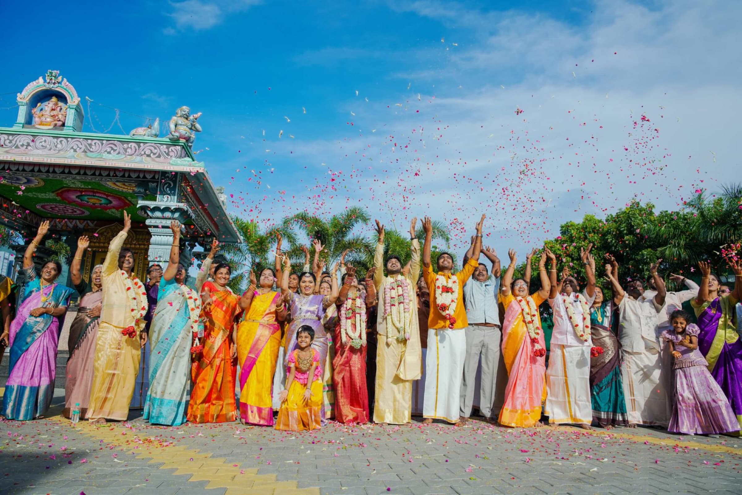 Wedding families celebrating with a flower shower outside a temple in Tamil Nadu